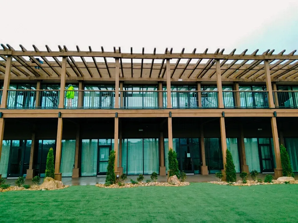 Two-story custom commercial pergola structure with balcony railings and wood columns, built by Sunshine Outdoor Living