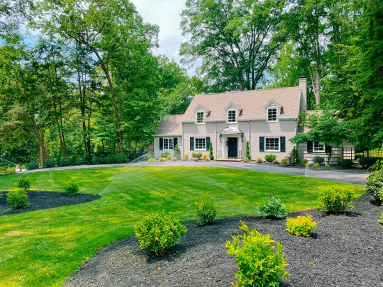 A large house with a large lawn in front of it surrounded by trees.