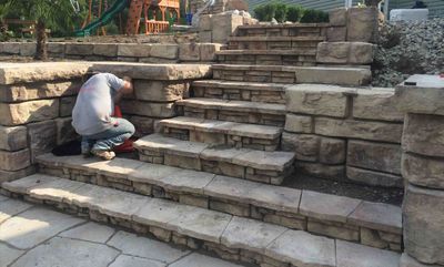 A man is kneeling down on a set of stone stairs.
