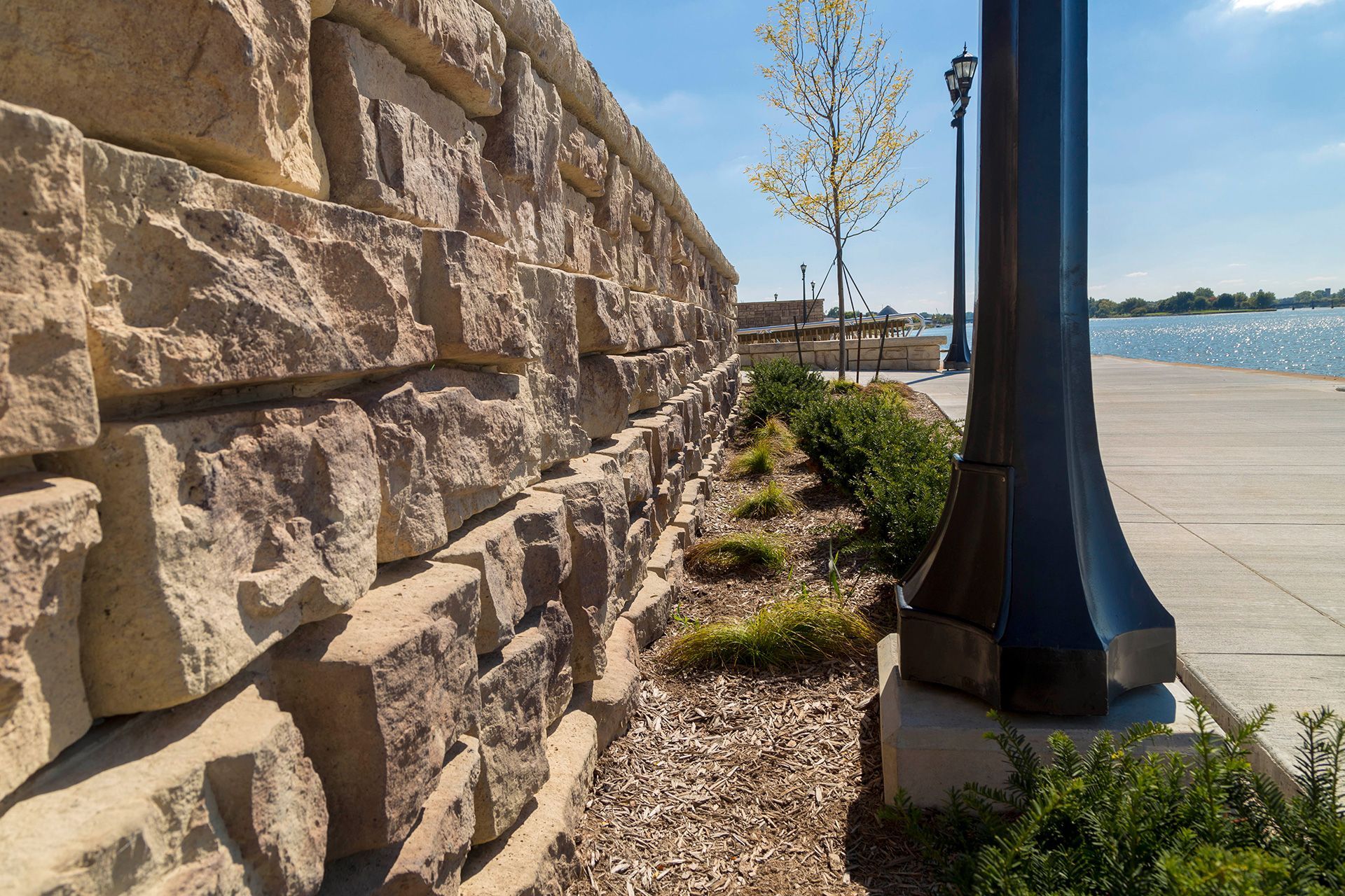 A stone wall with a lamp post in front of it
