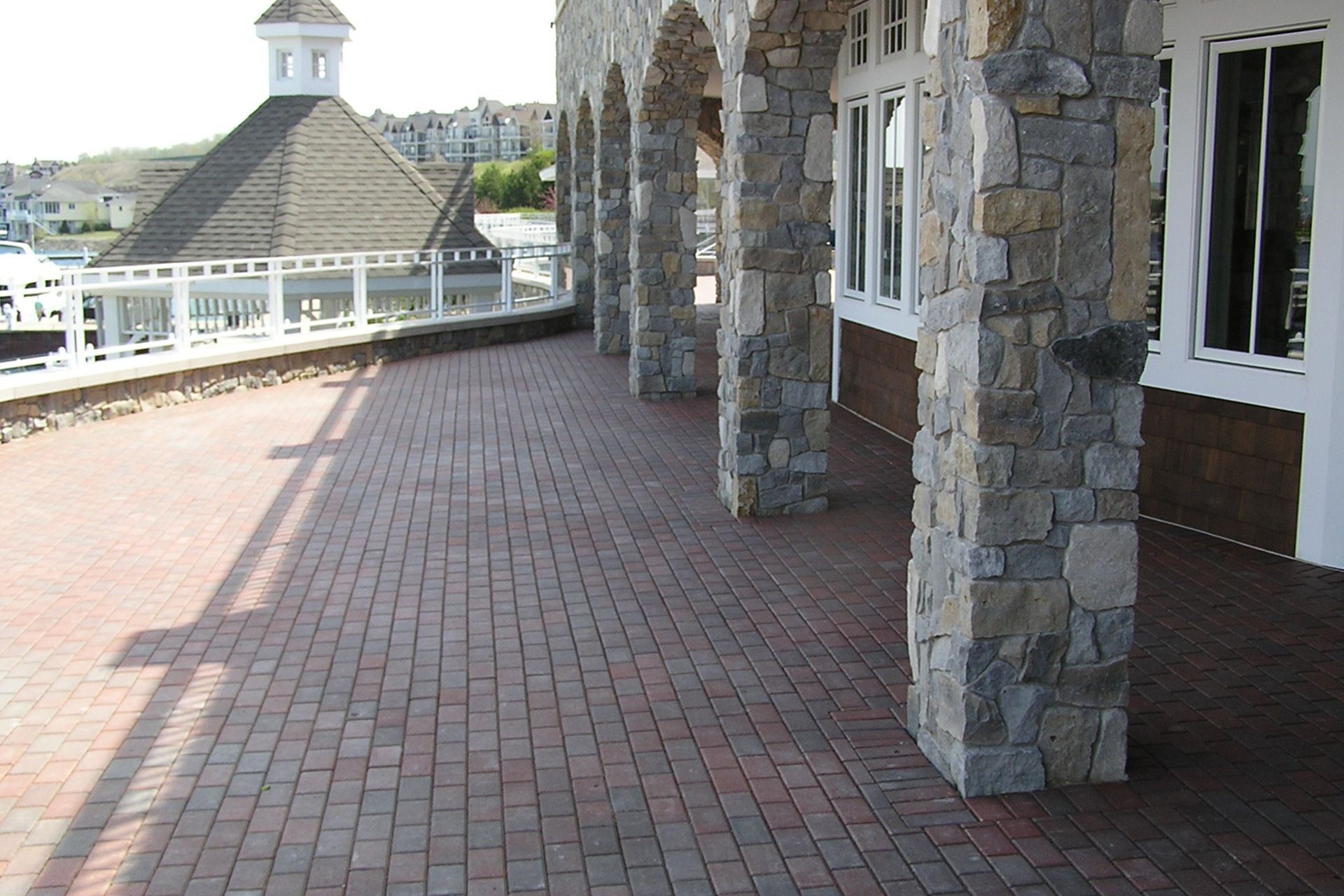 A brick walkway leading to a building with stone pillars