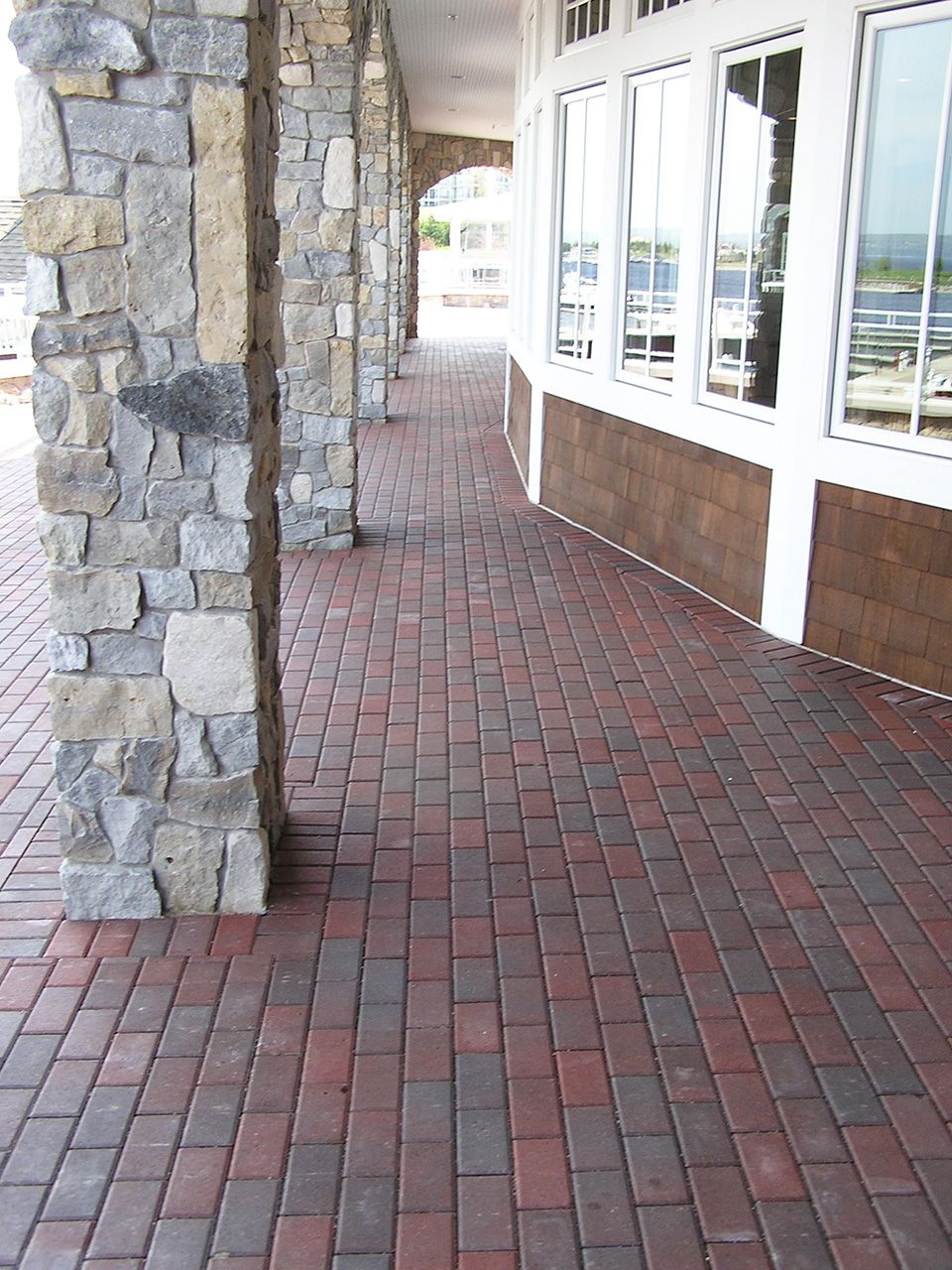A brick walkway leading to a building with columns and windows.