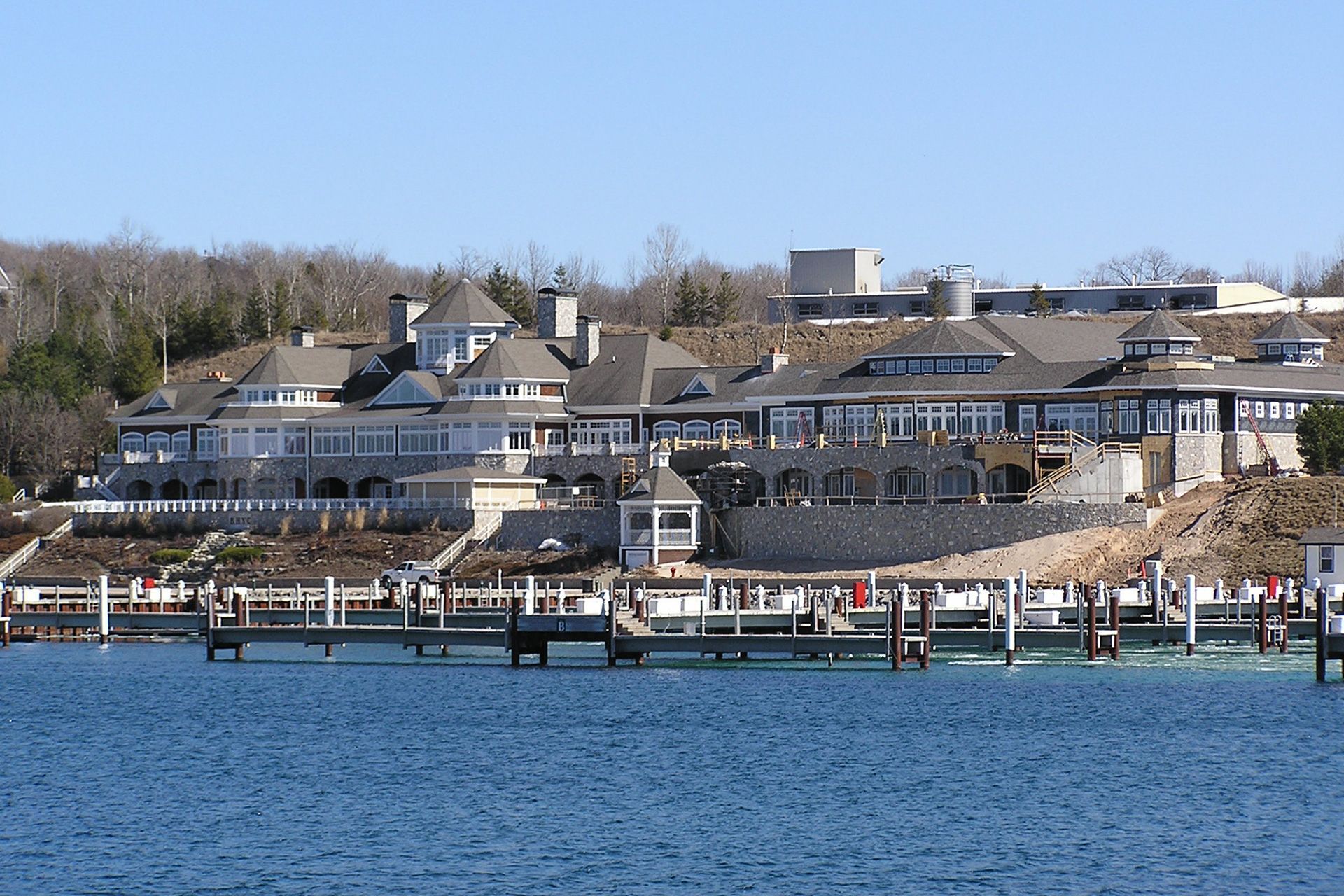 A large house sits on a hill overlooking a body of water