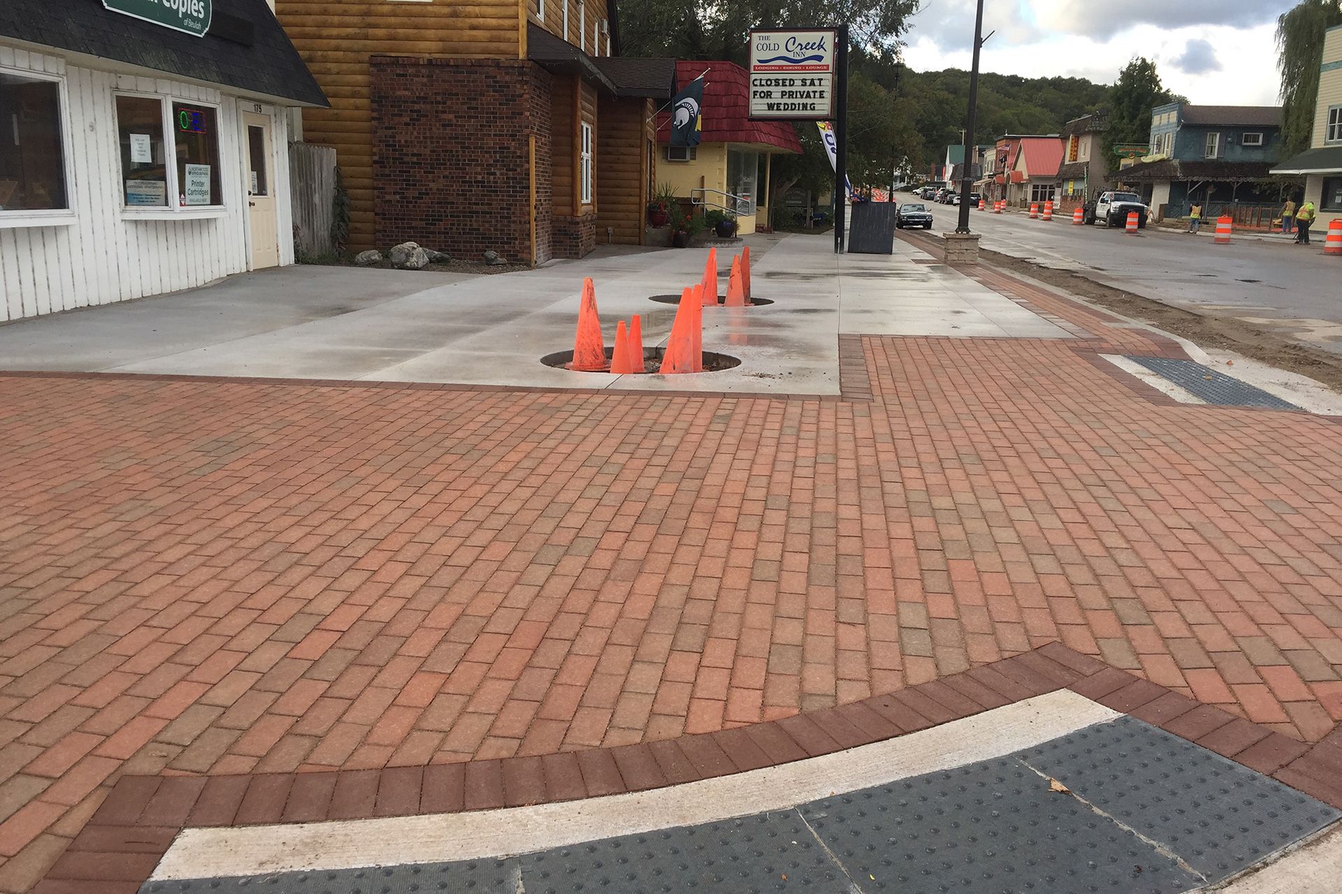 A brick walkway with orange cones on it in front of a building