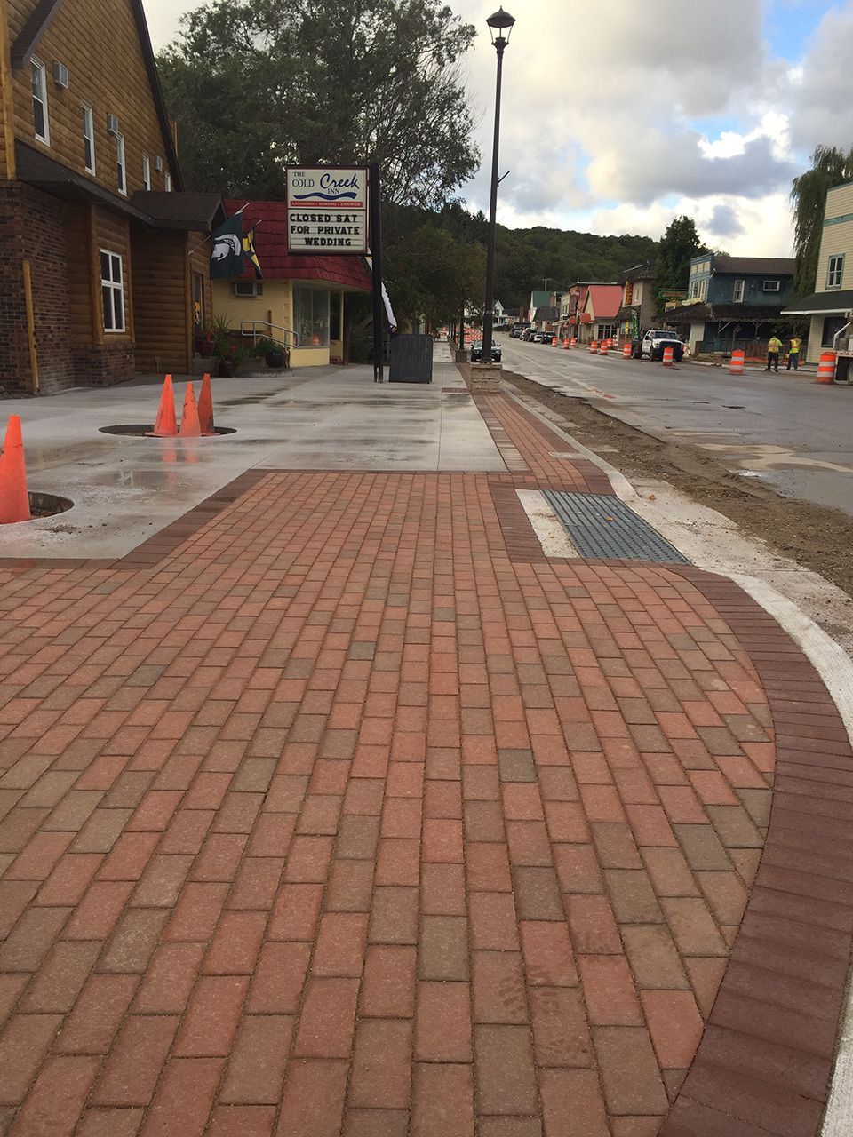 A brick walkway leading to a building with a sign on it