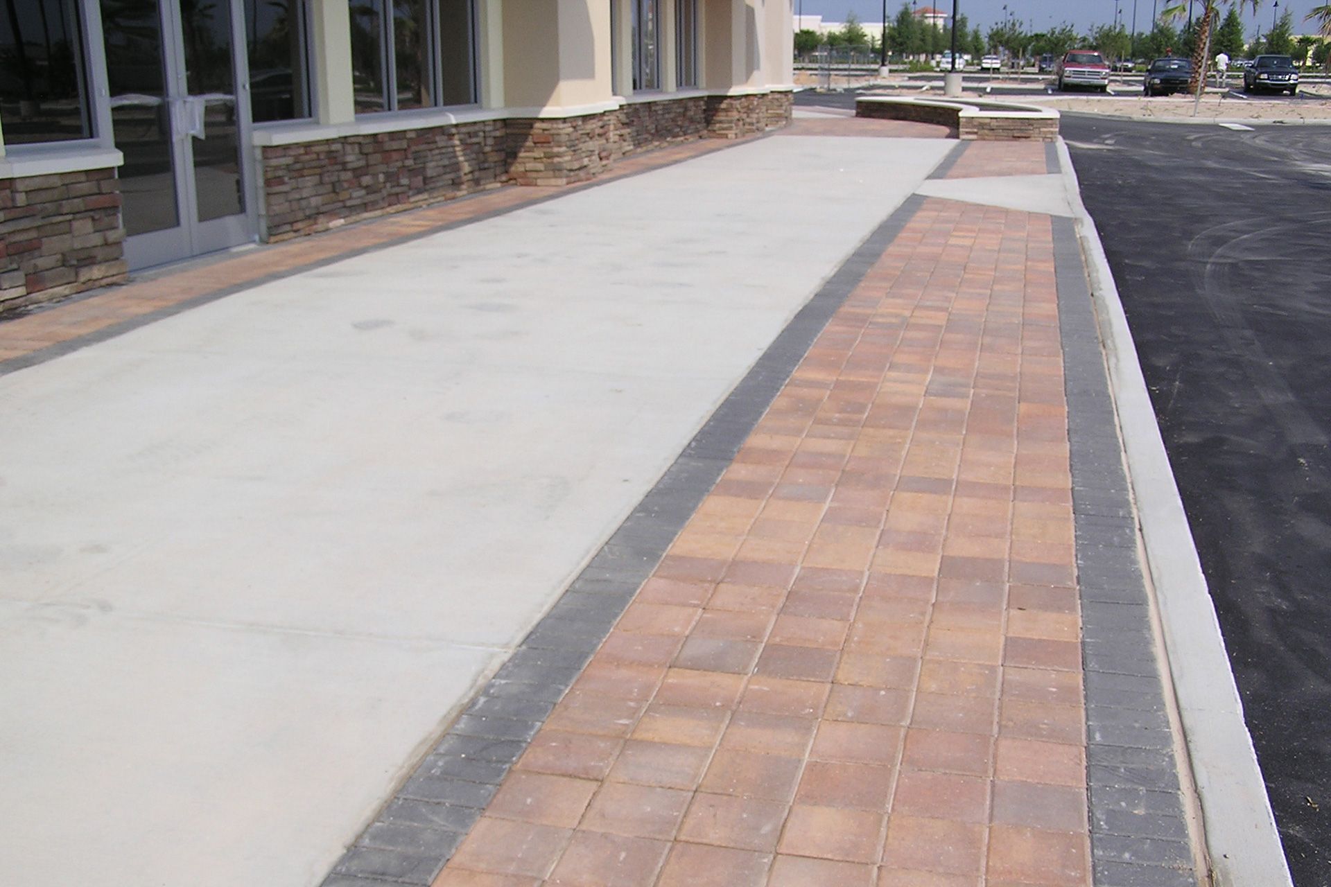 A sidewalk with bricks and concrete in front of a building