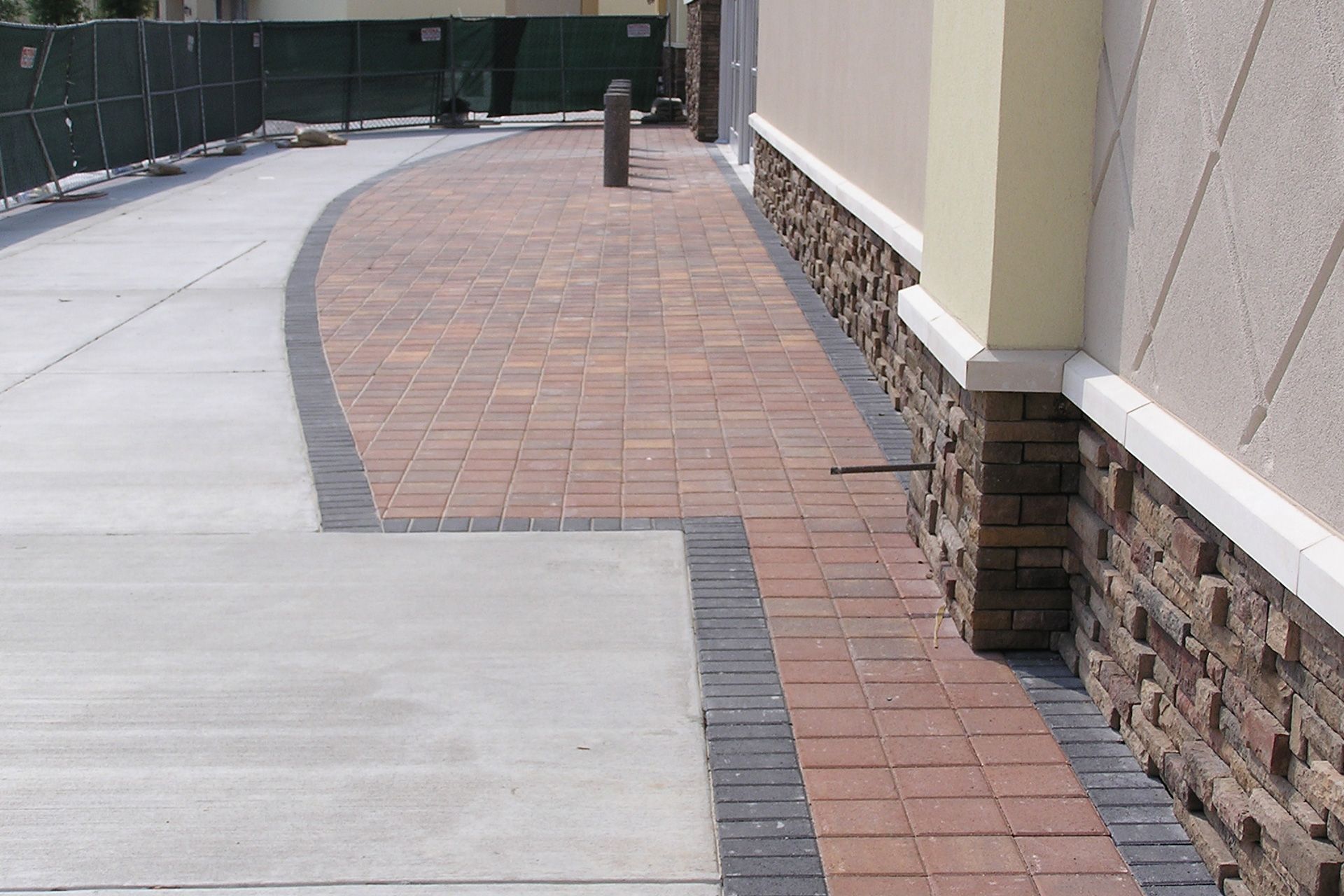 A sidewalk with bricks and concrete in front of a building