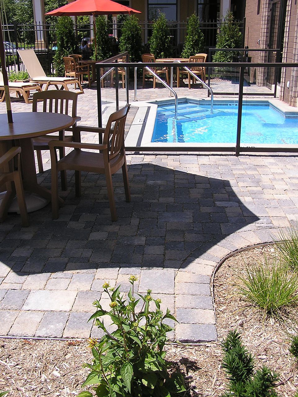 A patio with tables and chairs next to a swimming pool