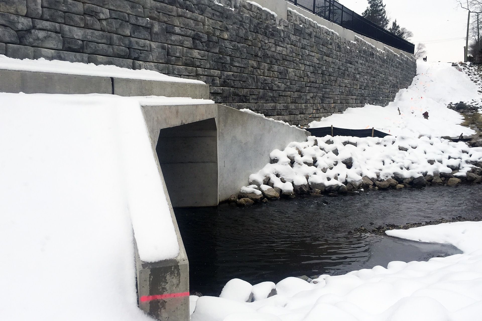 A snowy river with a stone wall in the background