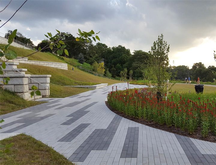 A brick walkway in a park with flowers on the side