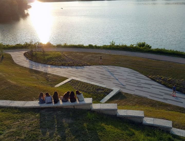 A group of people are sitting on a bench overlooking a lake.