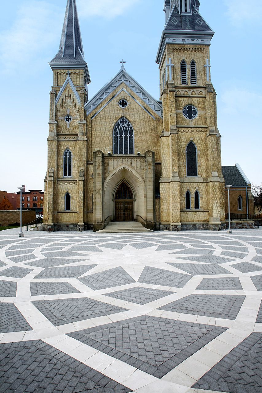 A large brick church with a circular pattern on the ground in front of it.
