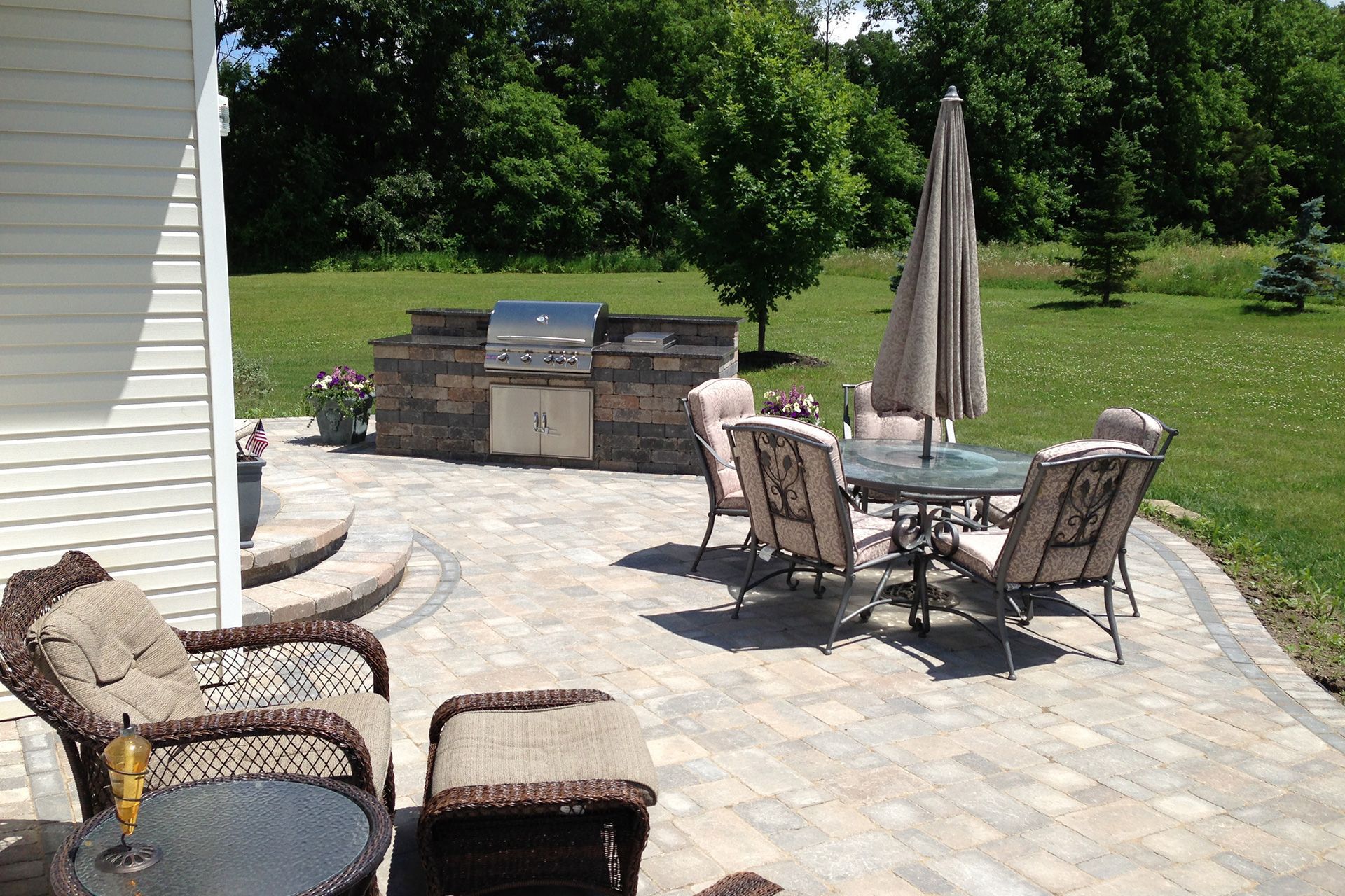 A patio with a table and chairs and a grill.