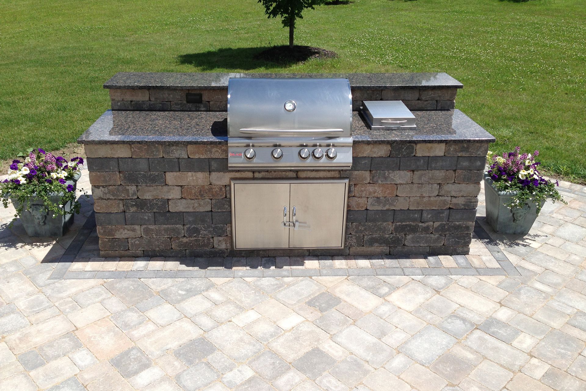 A grill is built into a stone wall on a patio