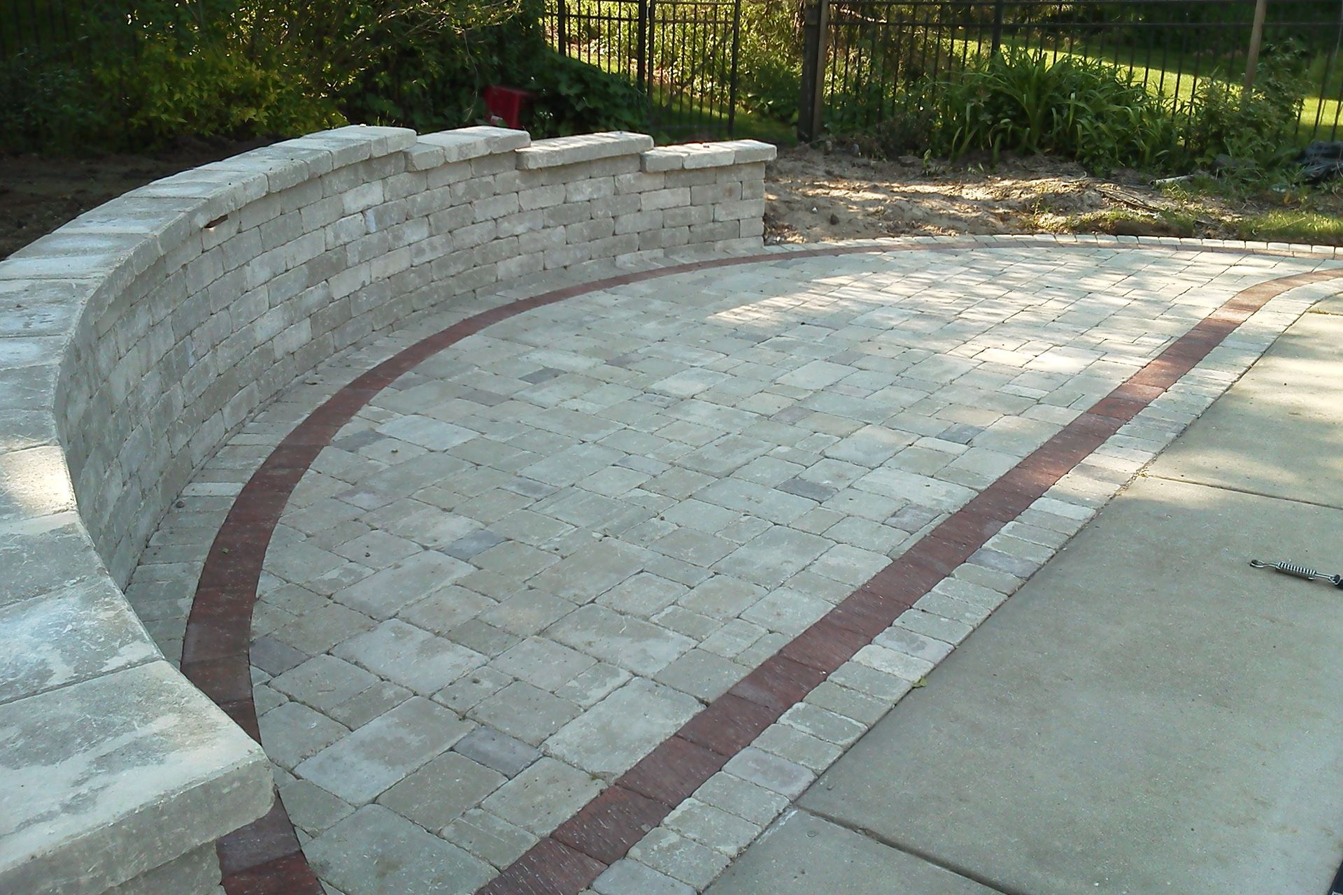 A brick walkway with a curved wall and a brick border