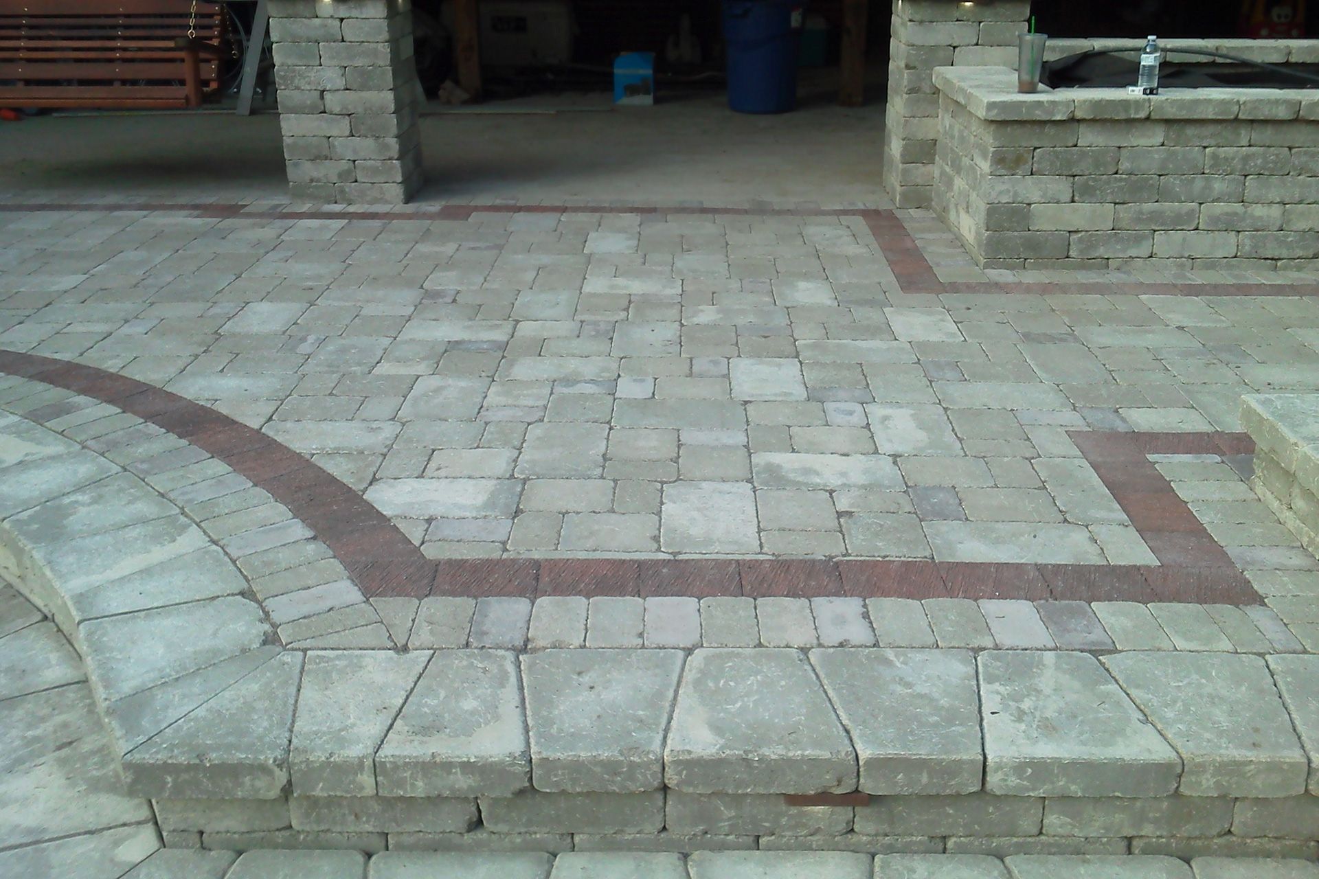 A brick patio with a red border and steps