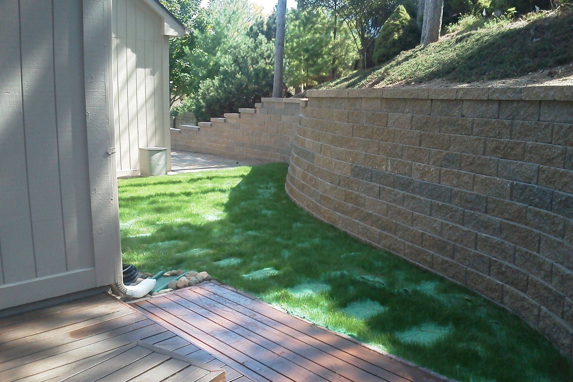 A brick wall surrounds a lush green yard
