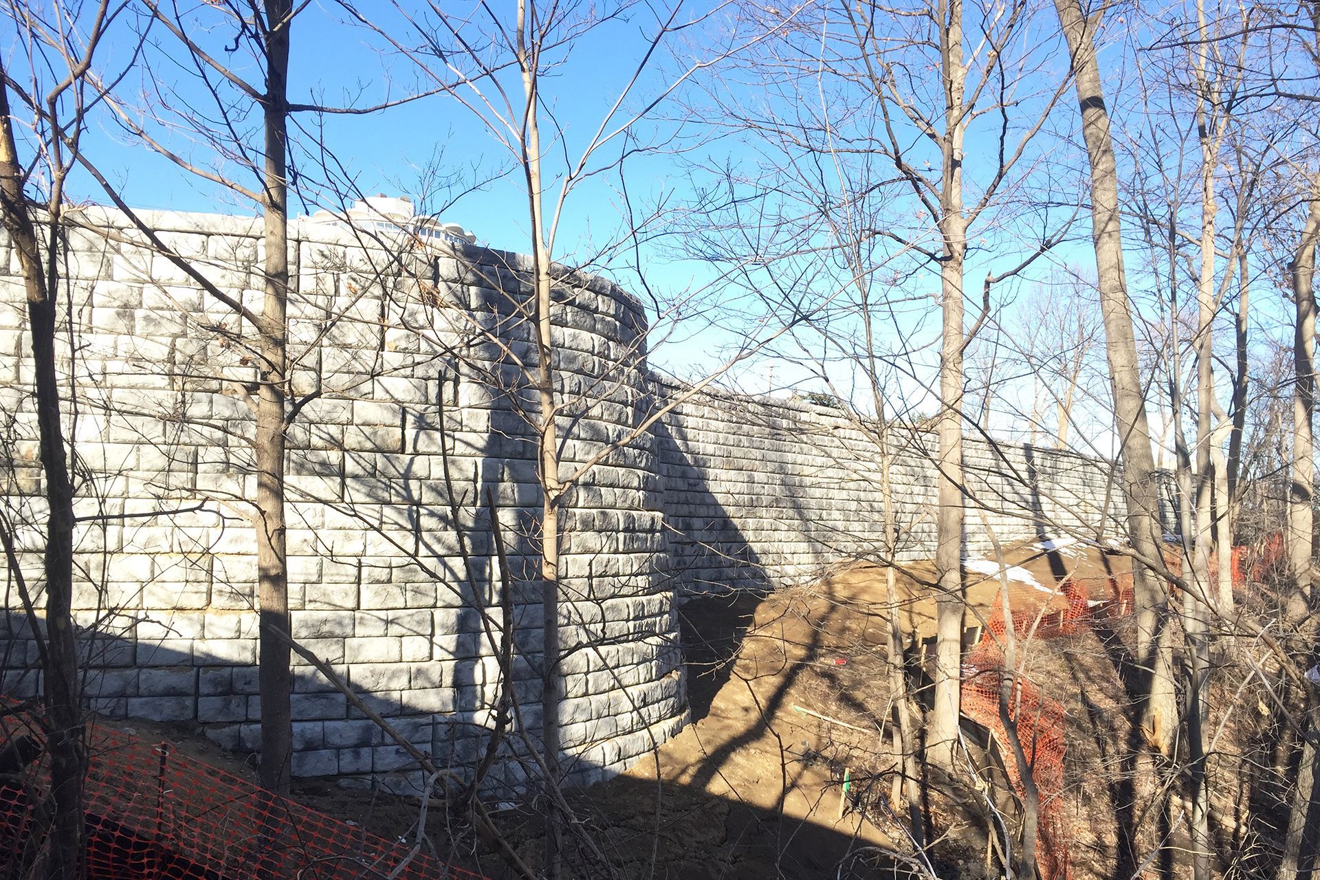 A stone wall is surrounded by trees on a sunny day.