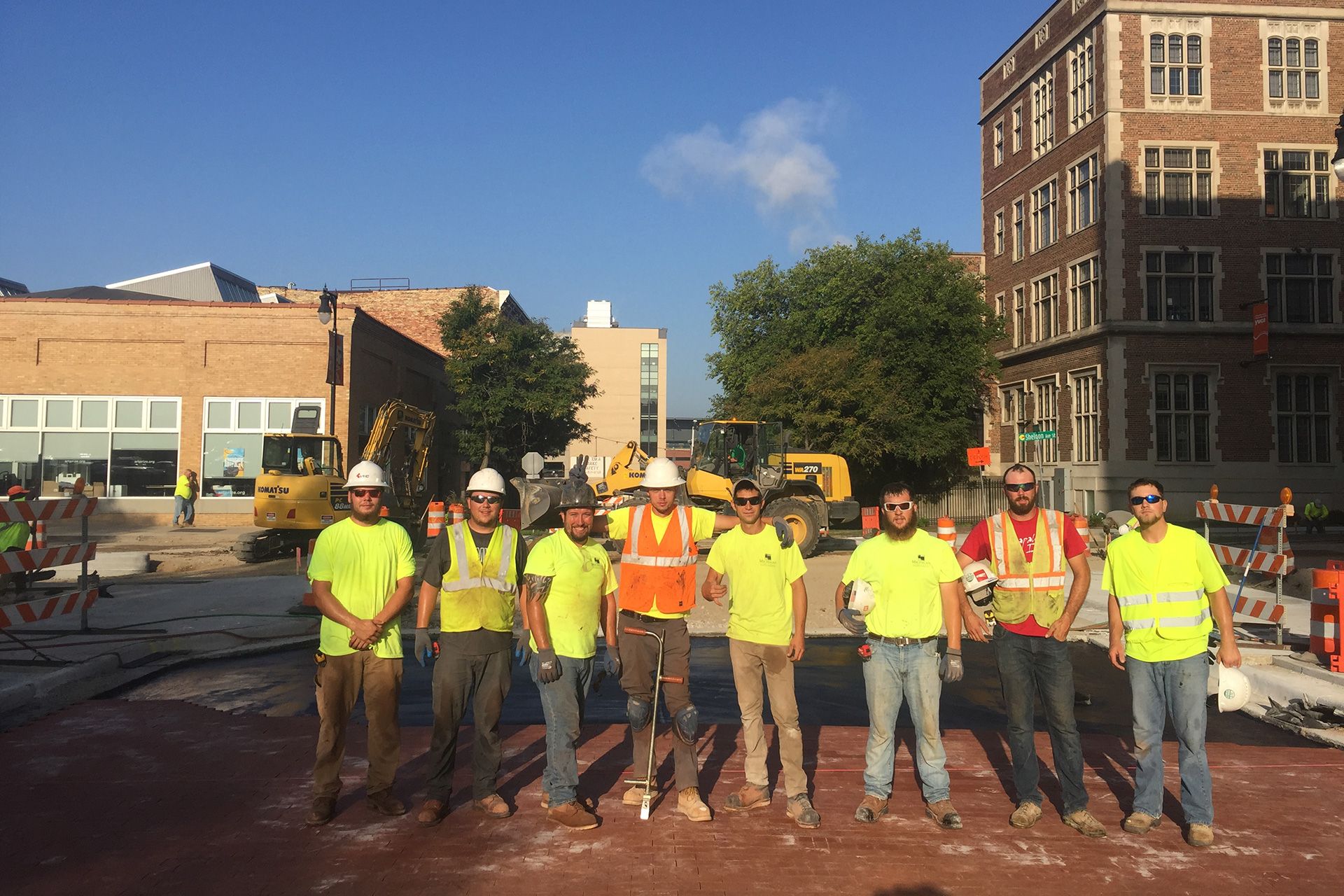 A group of construction workers are posing for a picture in front of a building.