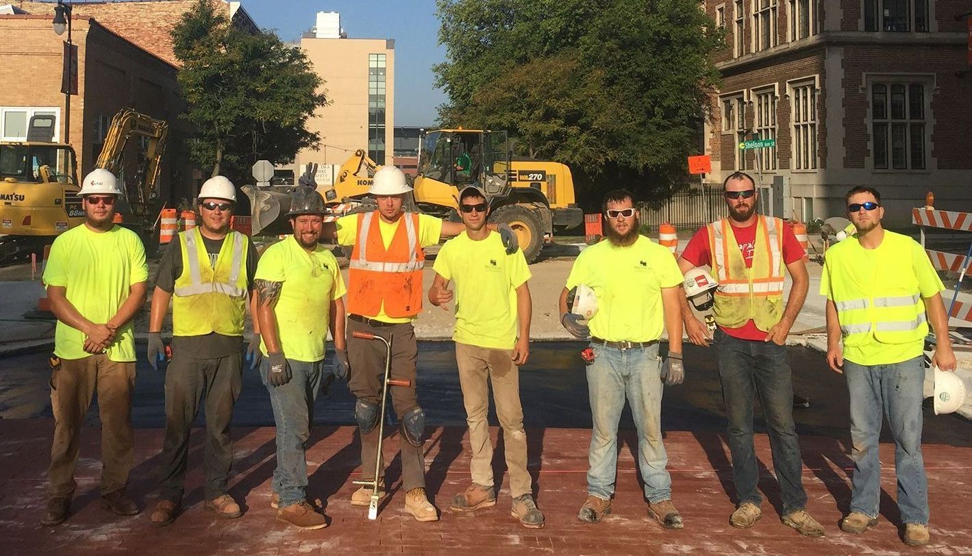 A group of construction workers are posing for a picture on a construction site.