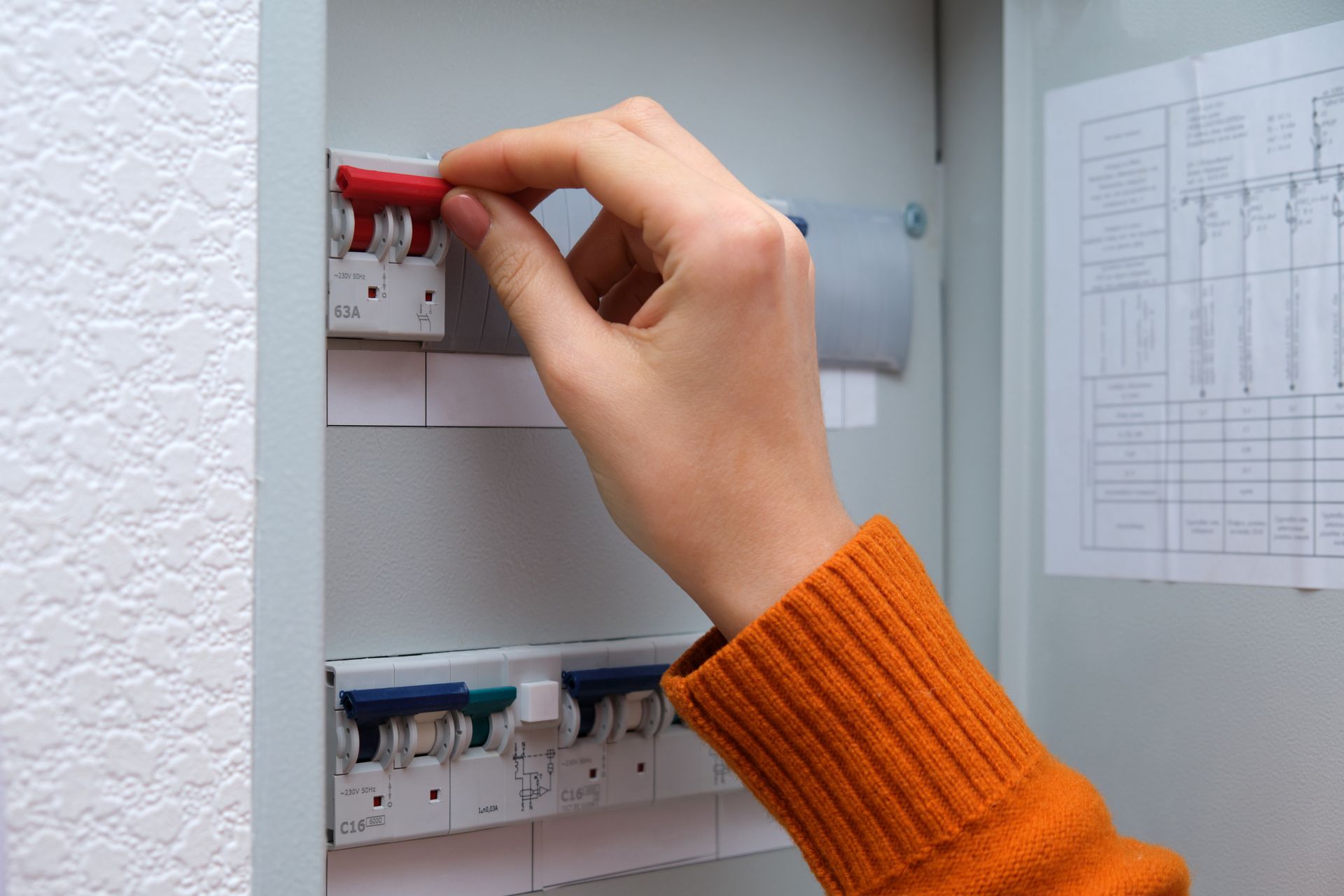 Hand turning a red switch on an electrical breaker panel