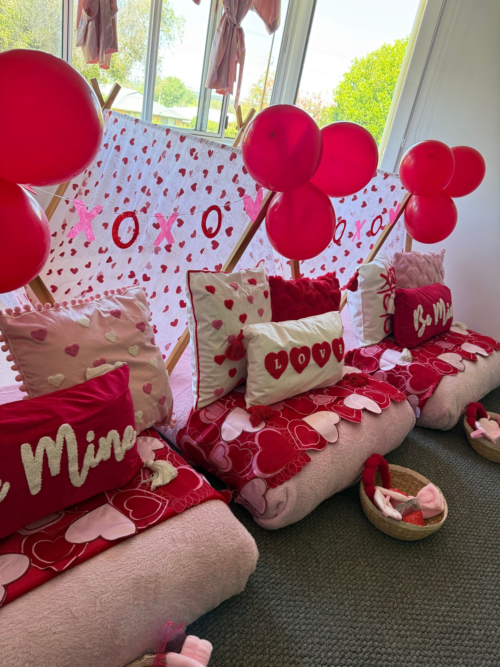 Valentine’s Day living room with red balloons, heart pillows, and a pink heart-patterned backdrop — Sweet Parties & Braids in Tatton, NSW
