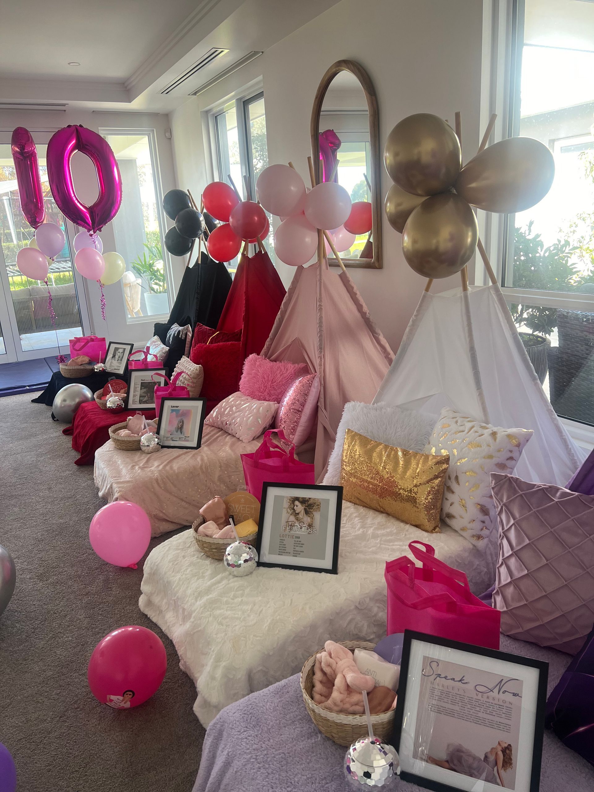 A birthday party setup with teepees, pillows, blankets, and balloons in shades of pink, gold, and black. — Sweet Parties & Braids in Tatton, NSW