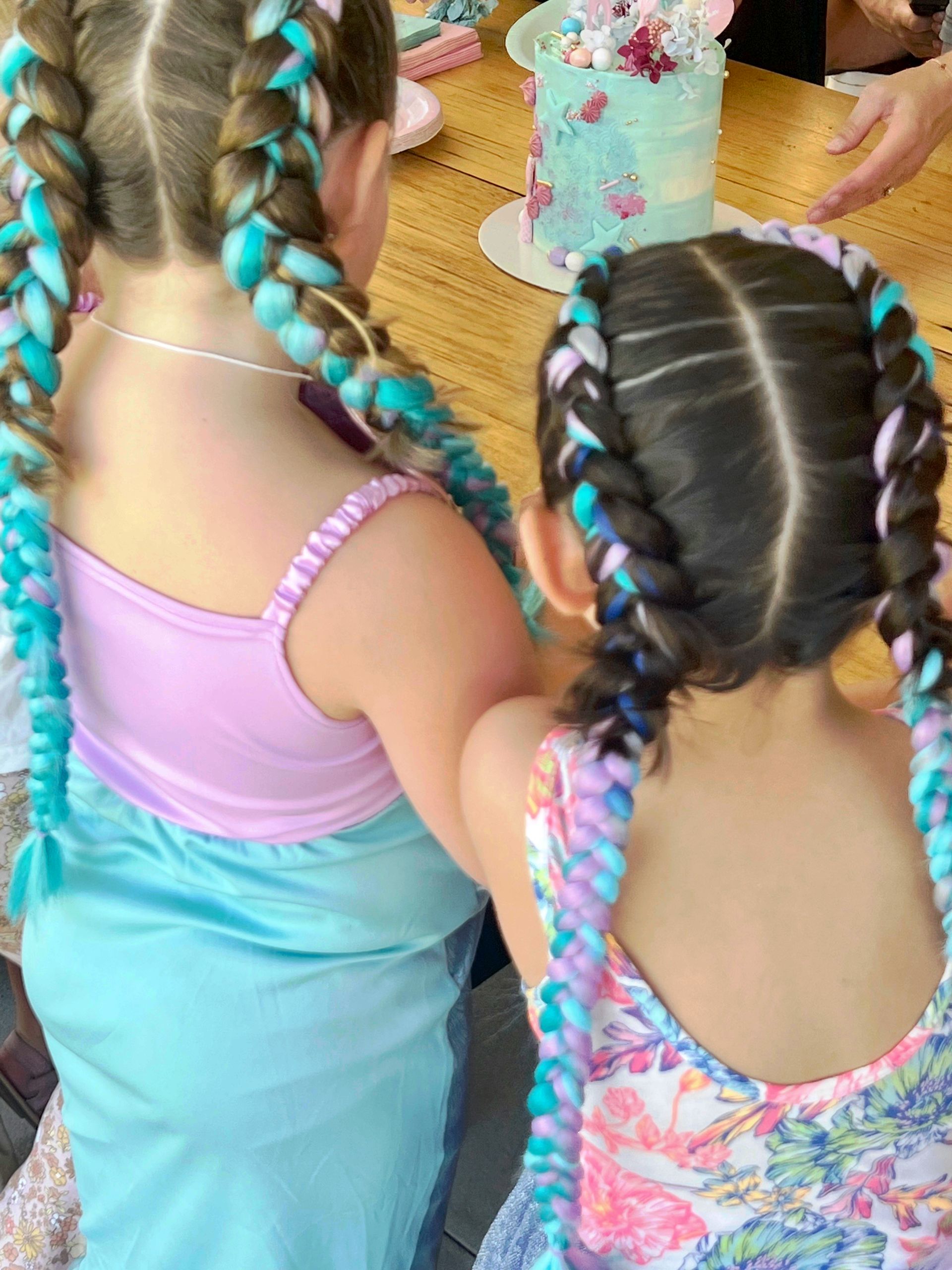 Two children with braided hair standing at a table with a pastel cake and party decorations β Sweet Parties & Braids in Tatton, NSW