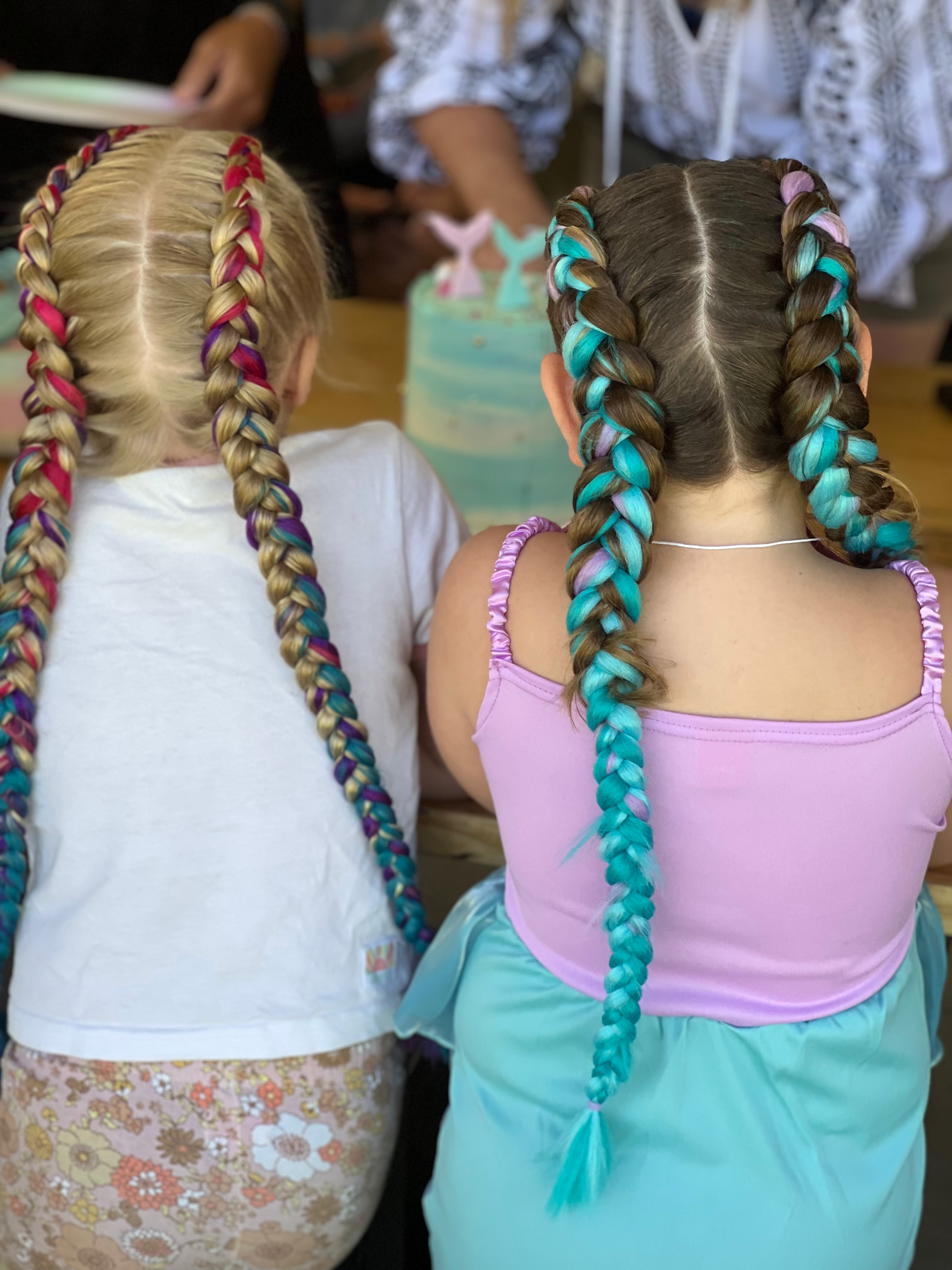 Two children with long braided hair and colorful extensions seen from behind at an outdoor event β Sweet Parties & Braids in Tatton, NSW