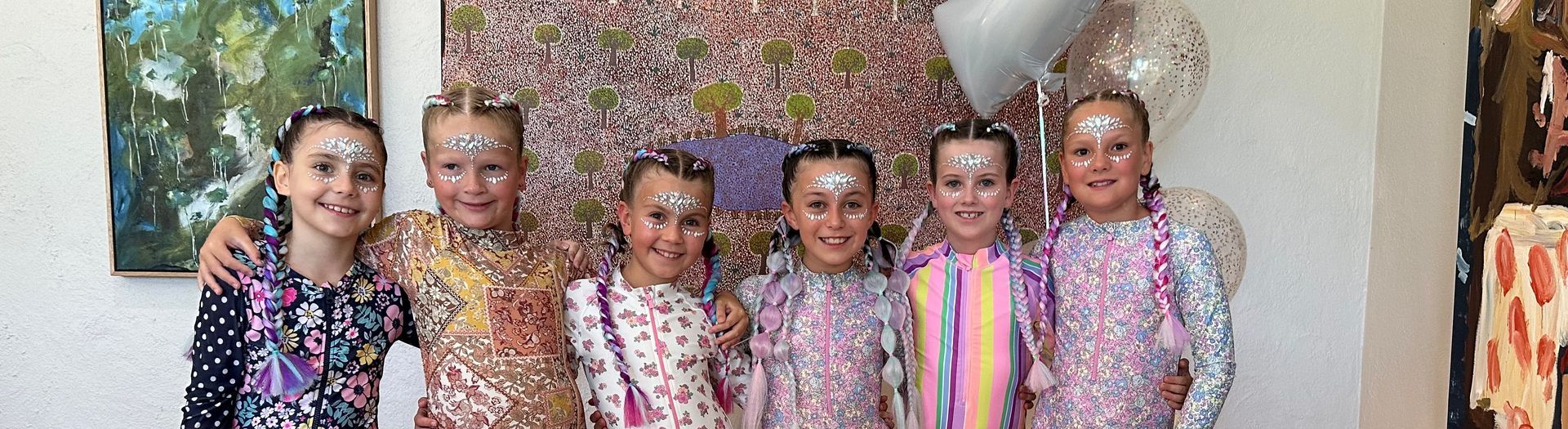 Six children standing together in colorful outfits, smiling in front of a floral backdrop β Sweet Parties & Braids in Tatton, NSW