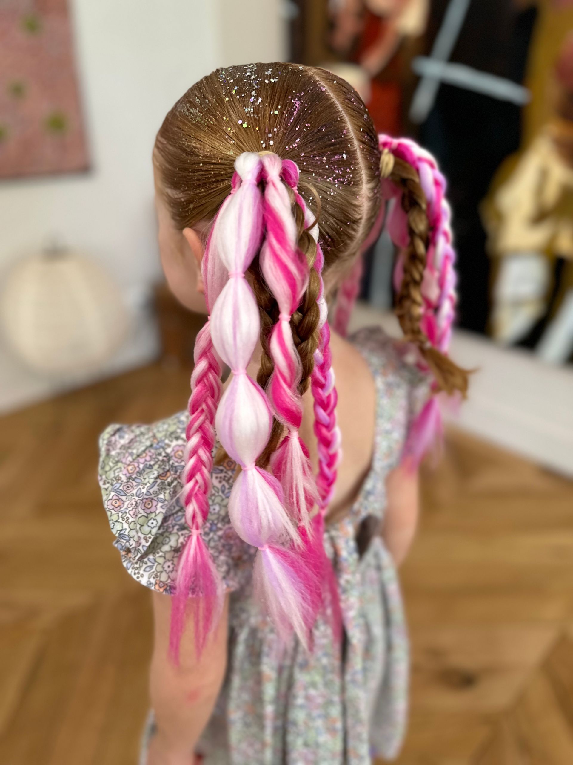 Child with glittery braided pink-and-blond hair in a dress, viewed from behind indoors β Sweet Parties & Braids in Tatton, NSW