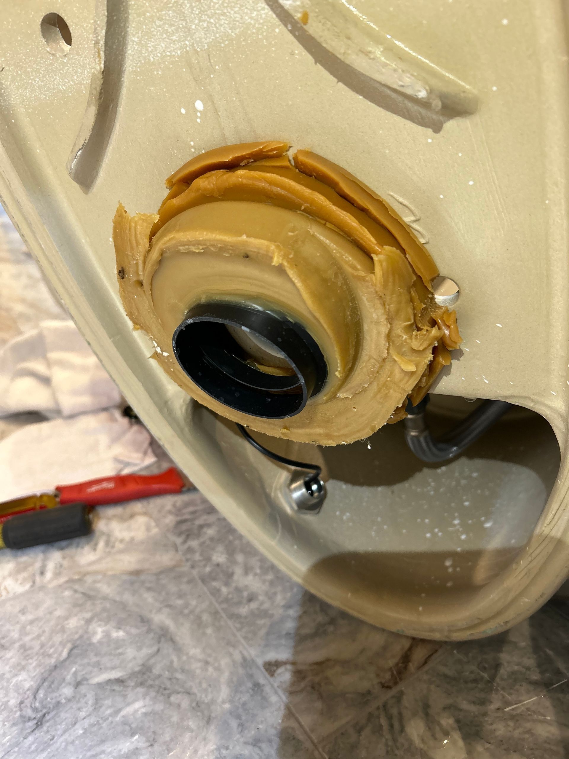 Close-up of a beige appliance opening with a black inner fitting and sealant around the rim.