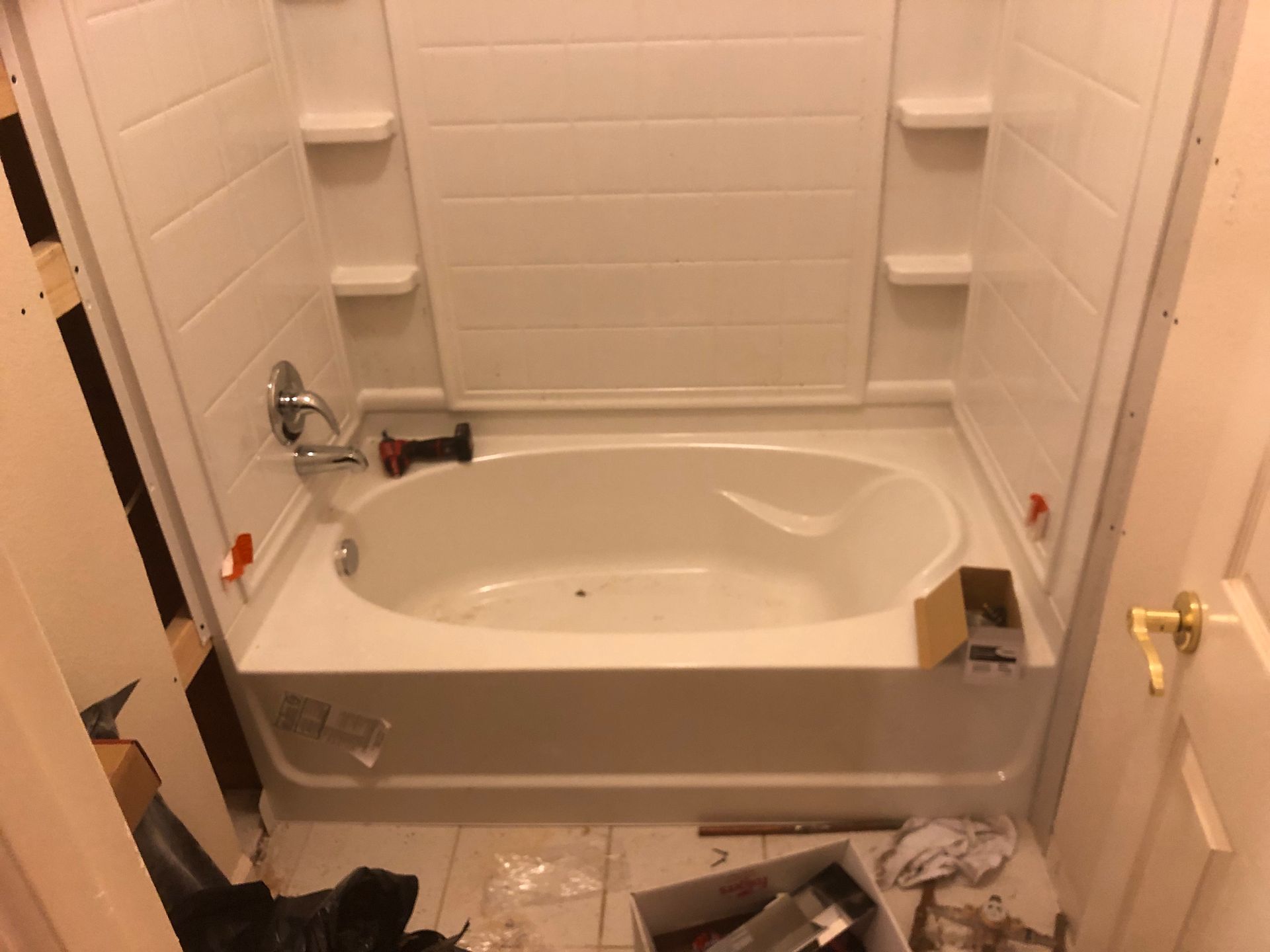 Small white bathroom with a bathtub, built-in shelves, and shower fixtures.