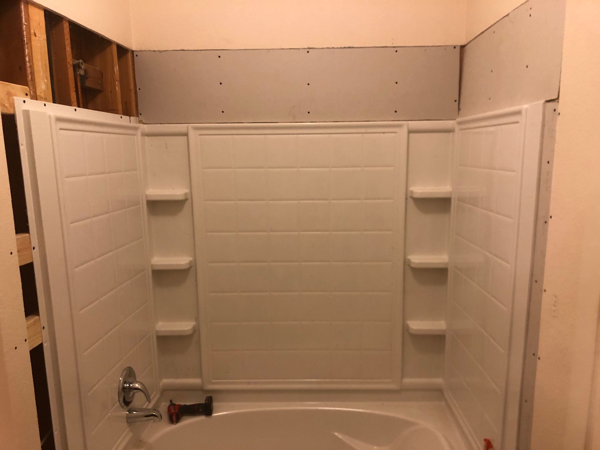 Empty white shower stall with built-in shelves and a chrome faucet on the left