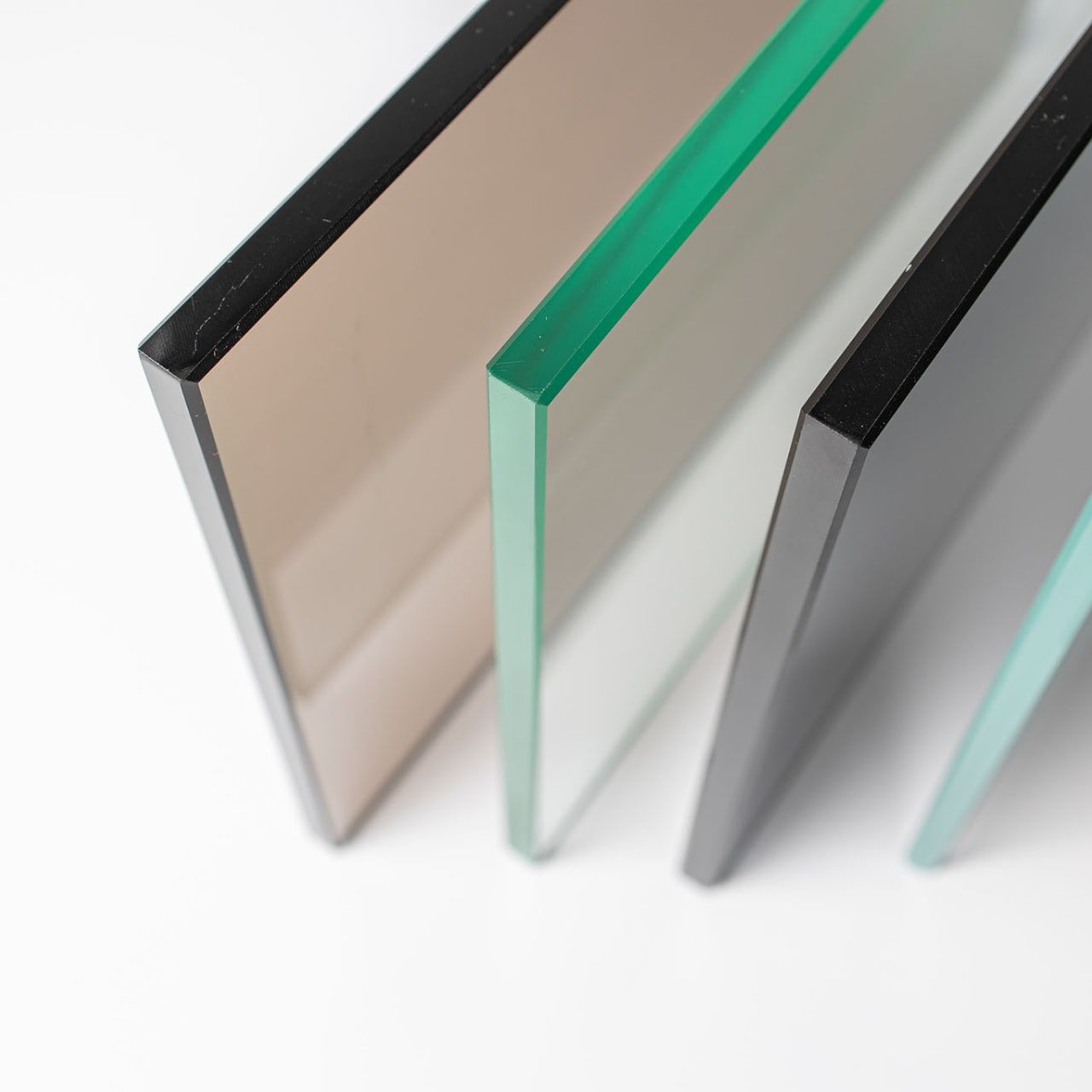 Three frosted glass panels in beige, green, gray, and aqua, standing upright on a white background