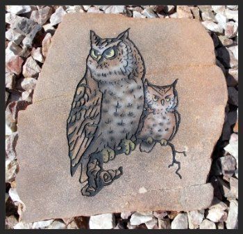 Two owls painted on a tan rock среди white stones