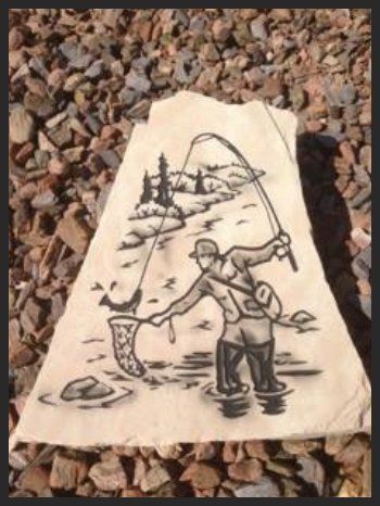 Hand-drawn sketch on a rock of two people fishing by water, with mountains in the background.