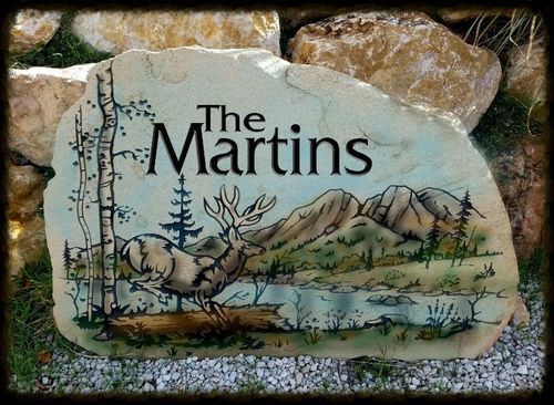 Stone sign reading “The Martins” with a painted desert scene of cactus, birds, and mountains.