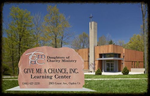 Sign for Dimensions of Charity Ministry and Give Me a Chance Learning Center outside a brick building