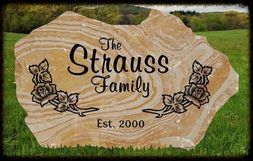 Personalized wooden sign reading “The Strauss Family” with floral design and “Est. 2000” on grass outdoors