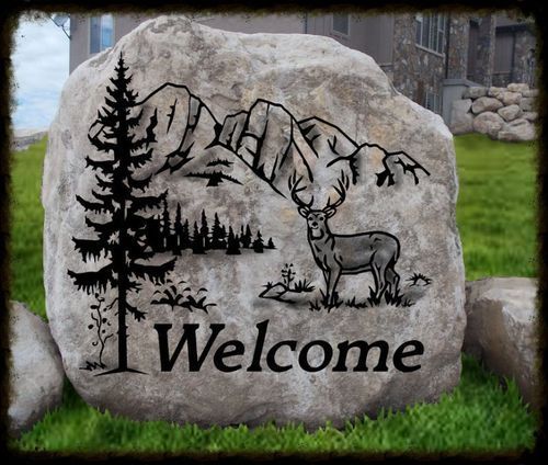 Welcome sign on a stone with black mountain, tree, and deer illustration
