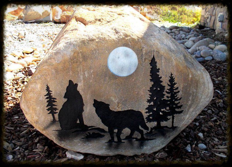Painted rock with black wolf and bear silhouettes under a bright moon in a forest scene