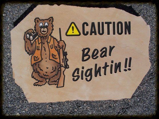 Caution sign with a cartoon bear and “Bear sightin!!” text on a stone plaque