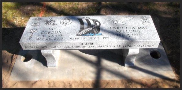 White engraved memorial bench in a sunny outdoor setting with shadows on the ground