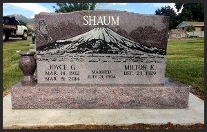 Granite grave marker with mountain engraving and the name “Shaum” in a cemetery.