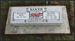Memorial stone bench with plaque reading “Baker” in a grassy setting.