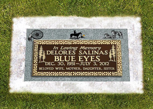 Gravestone plaque on grass with gray border and bronze center, reading Delores Salas Blue Eyes, 1951–2012