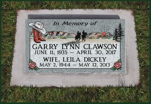 Memorial gravestone for Garry Lynn Clawson and wife Leila Dickey with flowers on grass