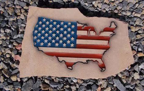 Torn U.S. flag shape on beige paper over gray gravel background