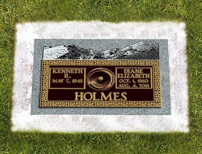 Gravestone plaque for Kenneth and Diane Holmes set in grass, bordered by white stone